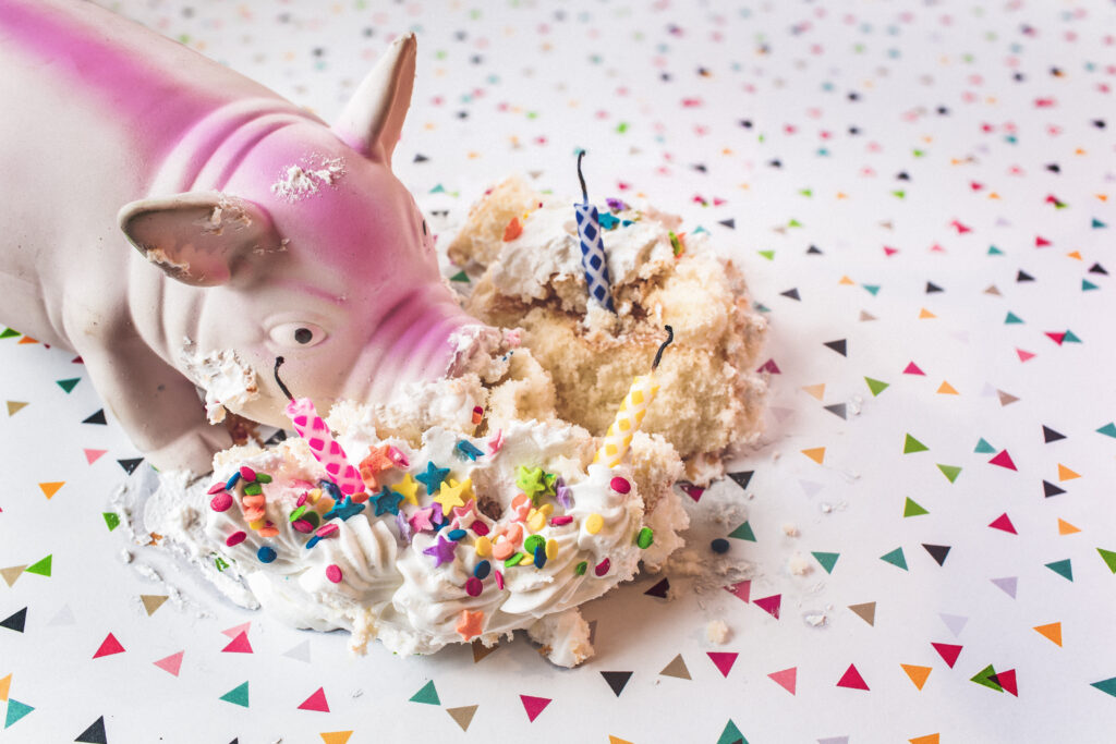 Geburtstagsschwein das eine Torte mit Kerzen frisst